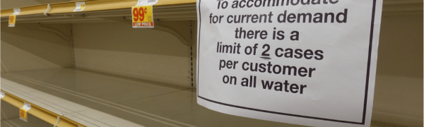 Demand Surge Example: Empty Store Shelves. Sign read: to accommodate for current demands, there is a limit of 2 cases per customer on all water